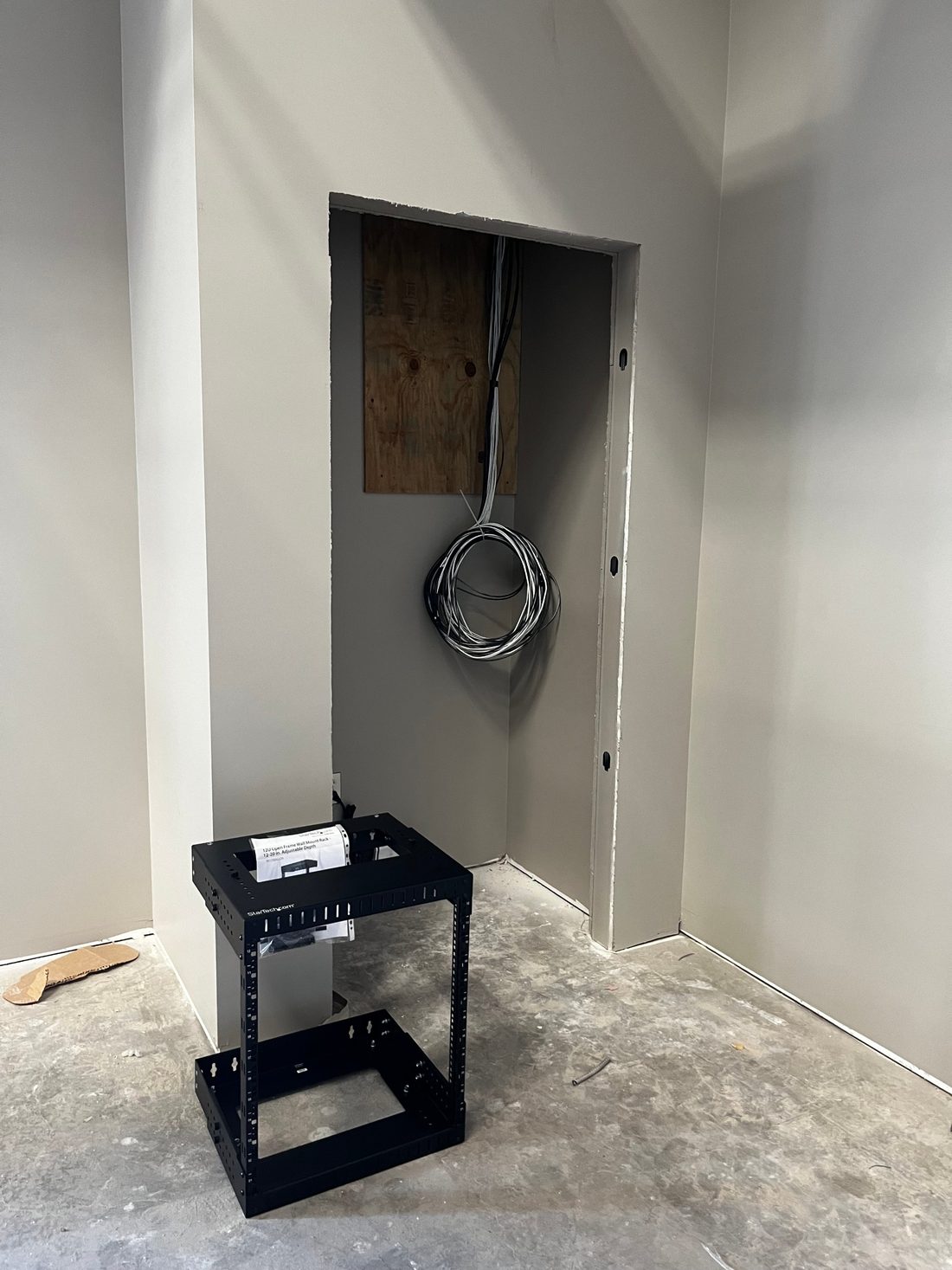 Network closet in a new office build-out with cable drops ready and a wall-mount rack waiting to be installed